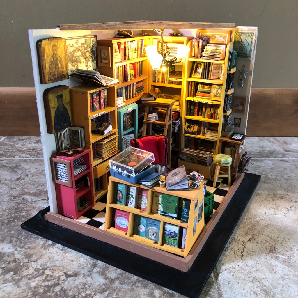 A miniature bookstore with tiny, detailed miniature books, bookshelves, furniture, and more.